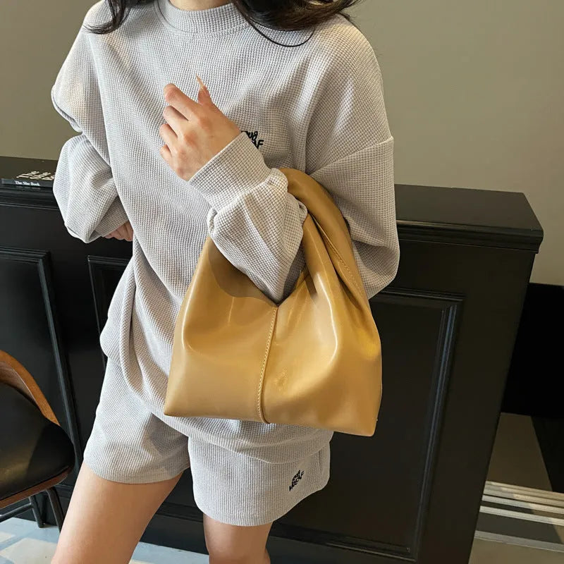Women's PU leather dumpling-shaped handbag in multiple colours with folding stitch details measuring 24x10x21cm
