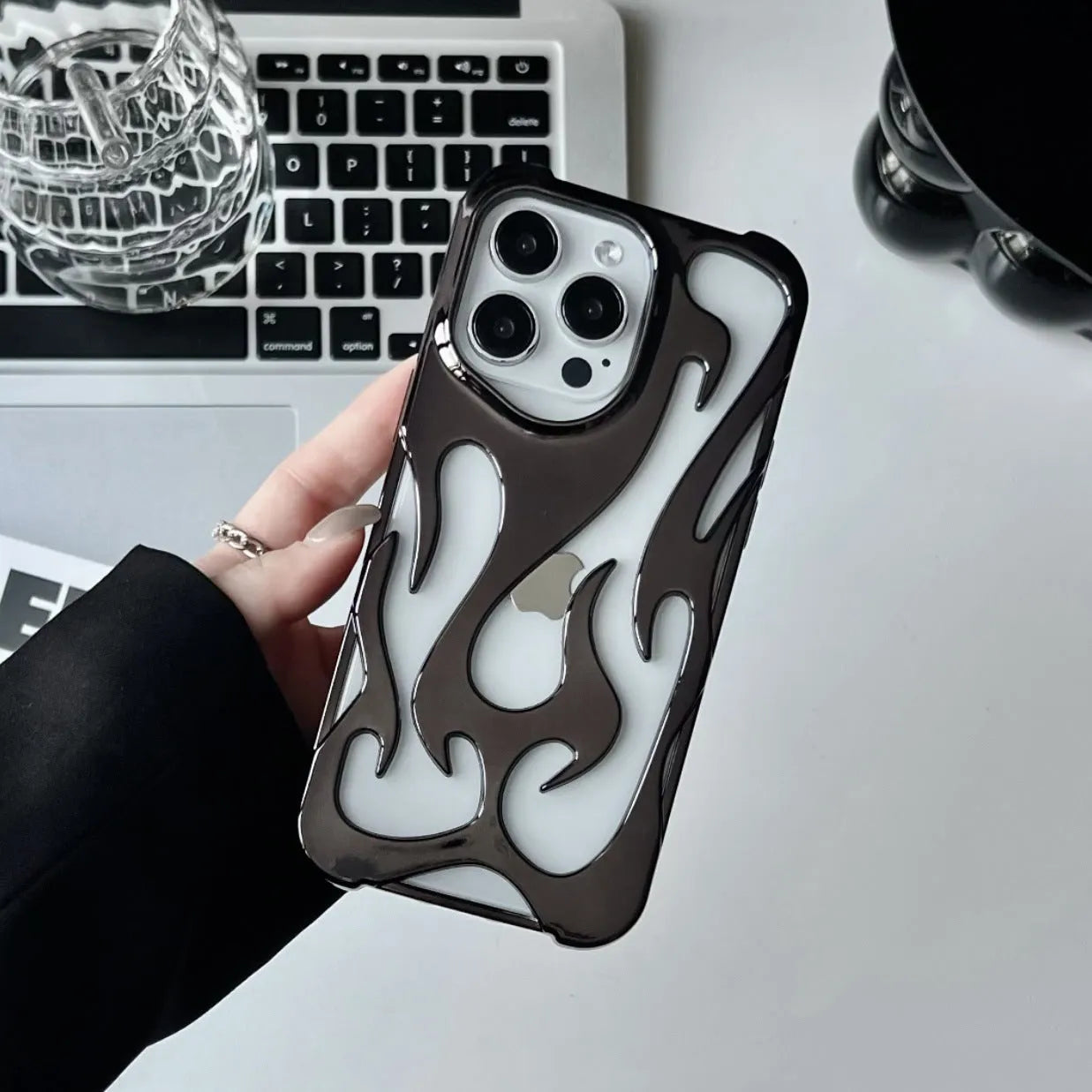 Electroplated hollow flame pattern soft TPU phone case for Apple iPhone on a table.