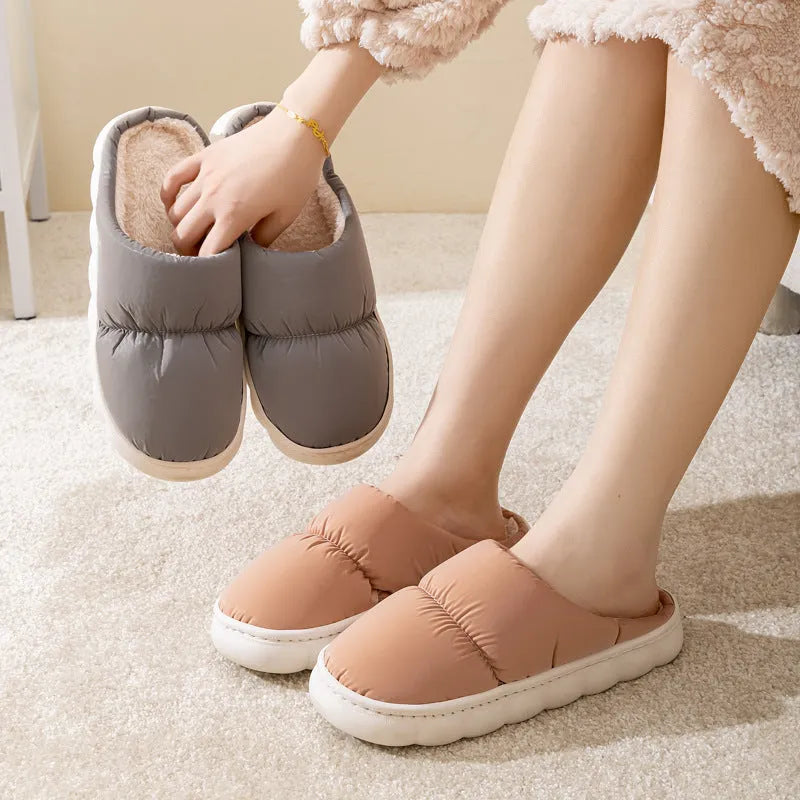 A pair of thick-soled house slippers with an artificial leather upper and plush lining, shown in a choice of colours.
