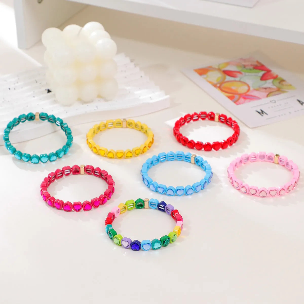 Colourful enamel heart-shaped charm on a stretch bracelet with diamond-textured alloy finish.