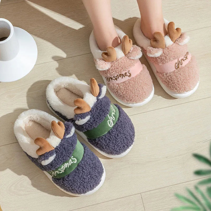 Pair of Christmas elk winter home slippers with suede upper and candy-coloured antler print on bedroom floor