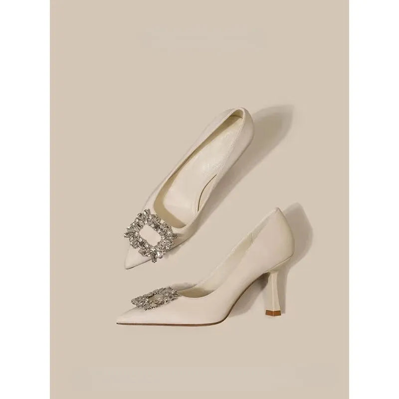 Creamy-white or black women's pointed toe high heels with a stiletto heel on a plain background.