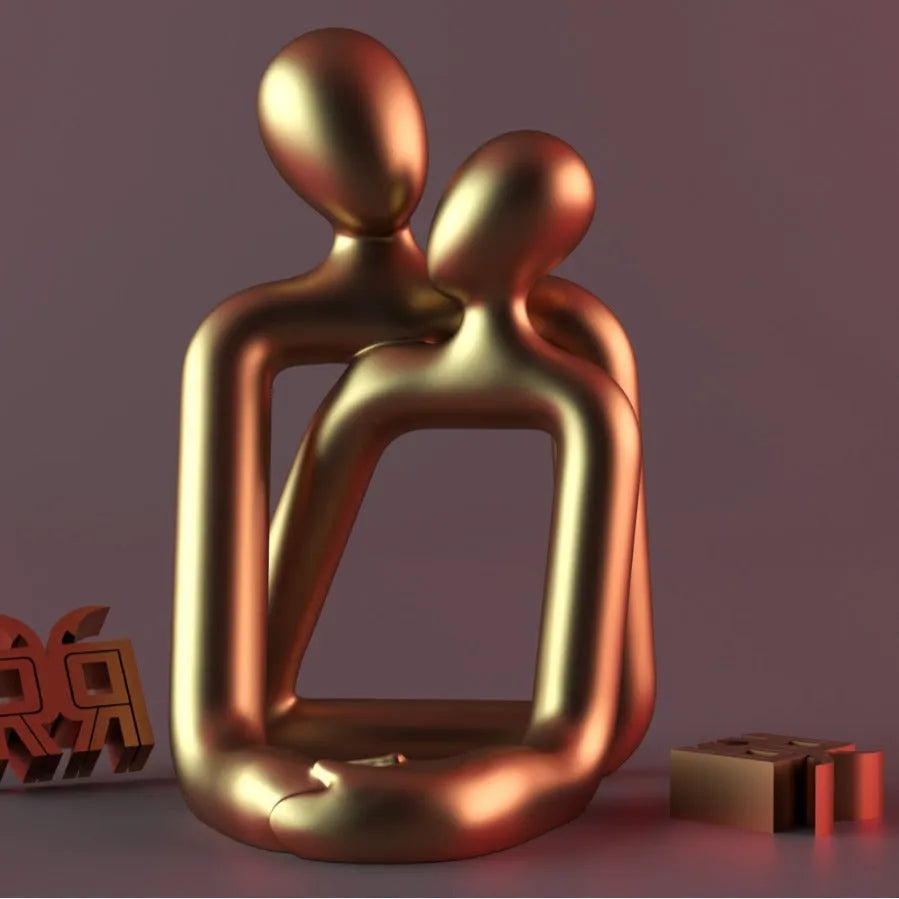 Modern resin sculpture of an embracing couple in milky white or gold finish on a wooden surface.