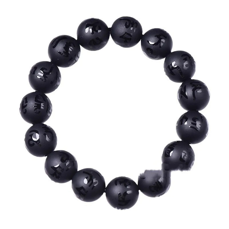 Close-up of a frosted black agate bracelet showing engraved Sanskrit mantra and Chinese-style patterns on a stone bead.