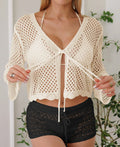Short apricot hollow woven women's cardigan blouse with bell sleeves on a hanger