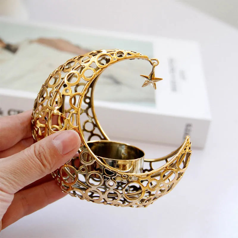 Gold crescent moon metal candle holder with hollow pattern on a wooden table