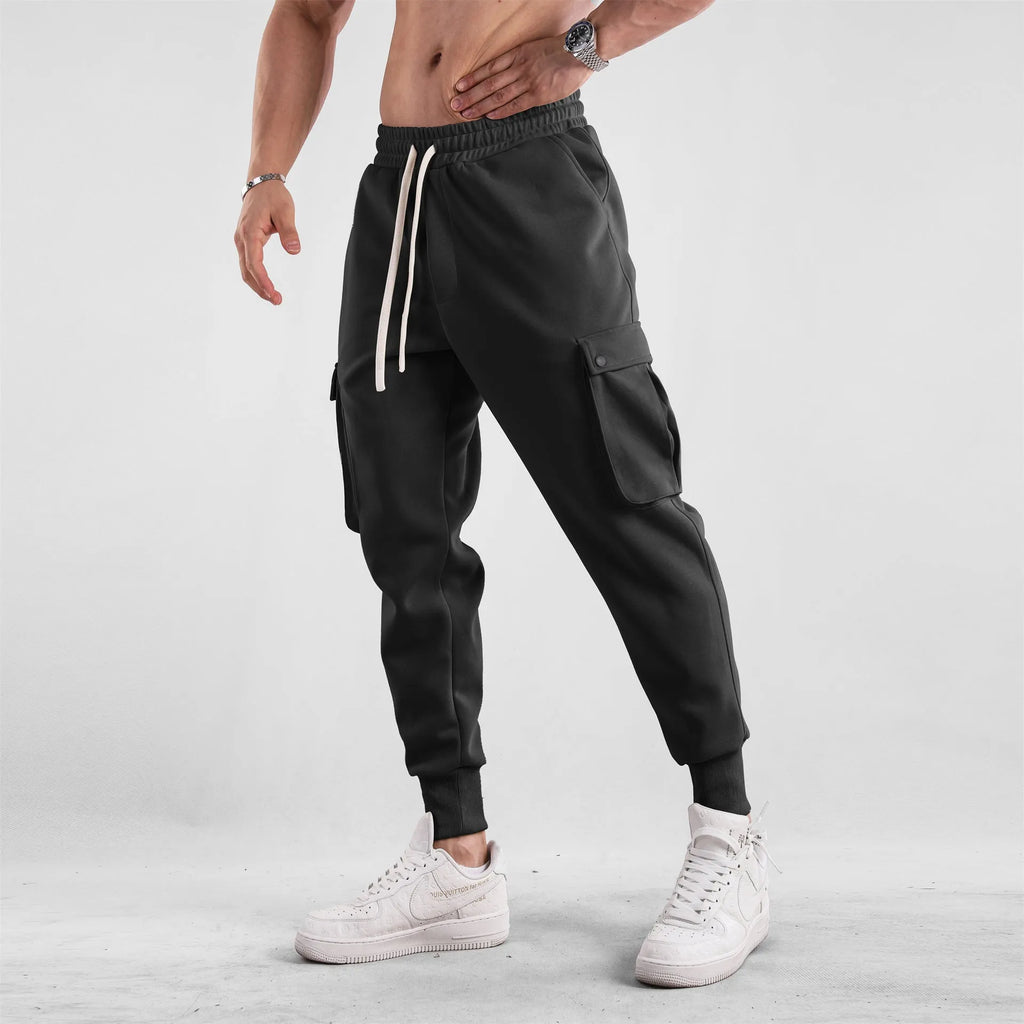 Men's loose grey cotton sports trousers with ankle ties and side pockets laid flat.