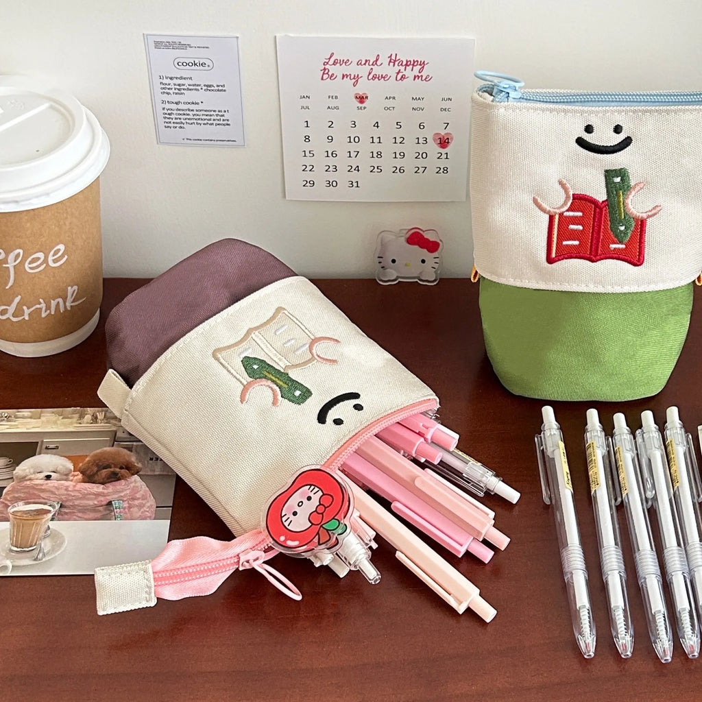 Brown collapsible Oxford fabric pencil case with zip, shown next to green version, measuring 17 by 14 cm.