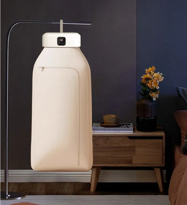 White cylindrical foldable portable clothes dryer with remote control on wooden surface