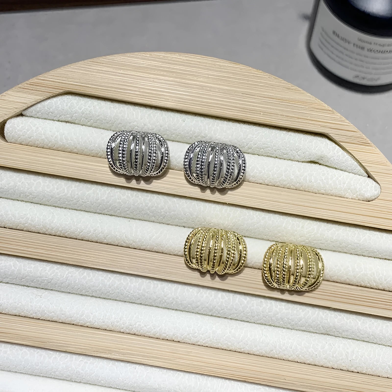 Multi layer metal wire C-ring earrings in gold and silvery colours on a neutral background