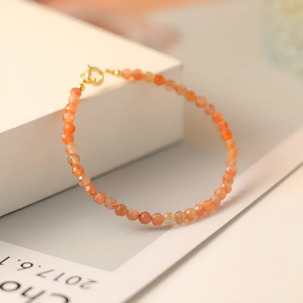 Close-up of a women's bracelet with small 3mm round sunstone beads on a string.