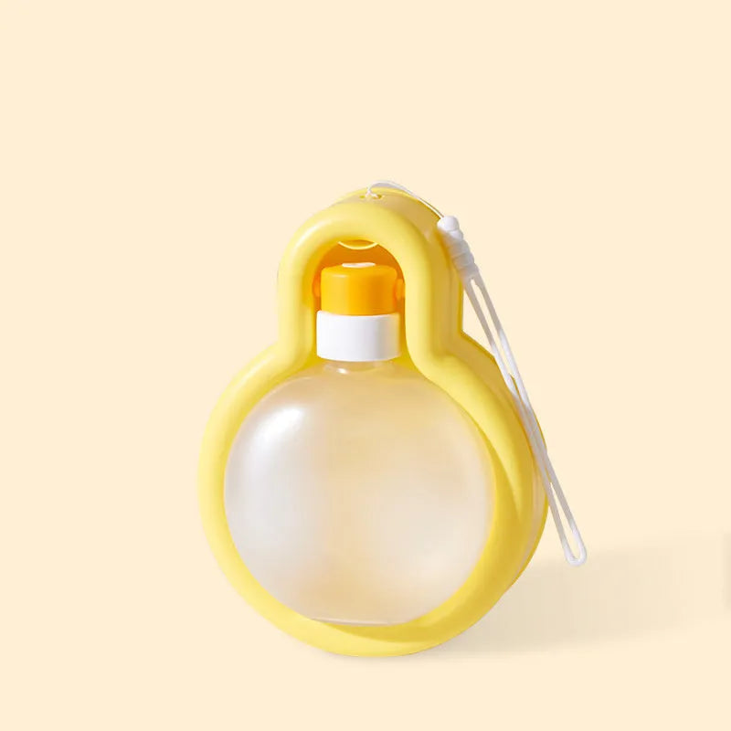 Green portable dog water bottle with pull-out drinking bowl on grass, showing travel cup design.