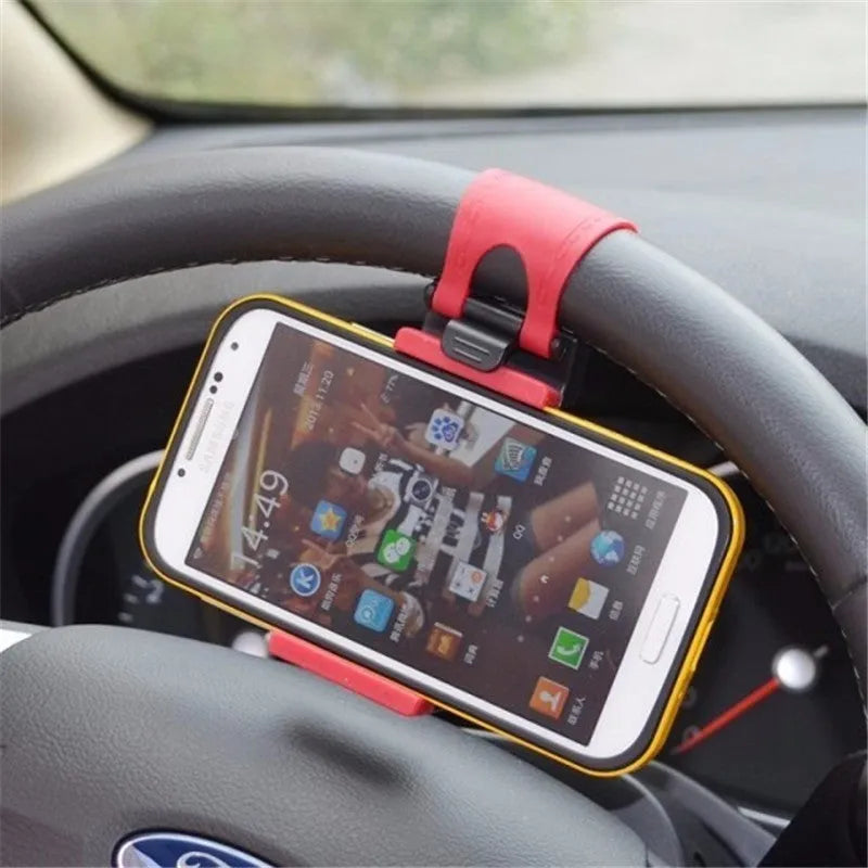 Black universal steering wheel phone holder clip mounted on a car steering wheel holding a smartphone.