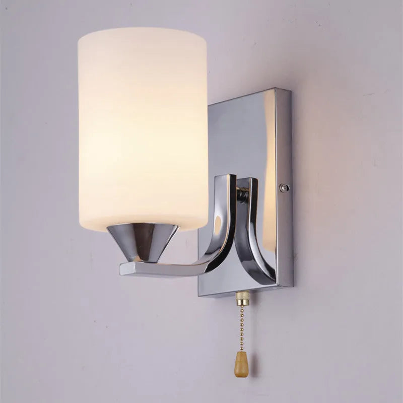 Chrome-plated wall lamp with clear glass shade mounted beside bed