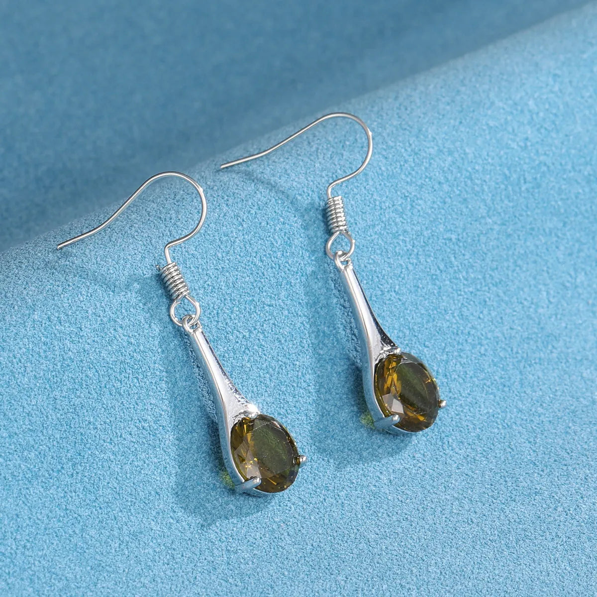A pair of simple olive green drop-shaped earrings with a retro style on a white background.