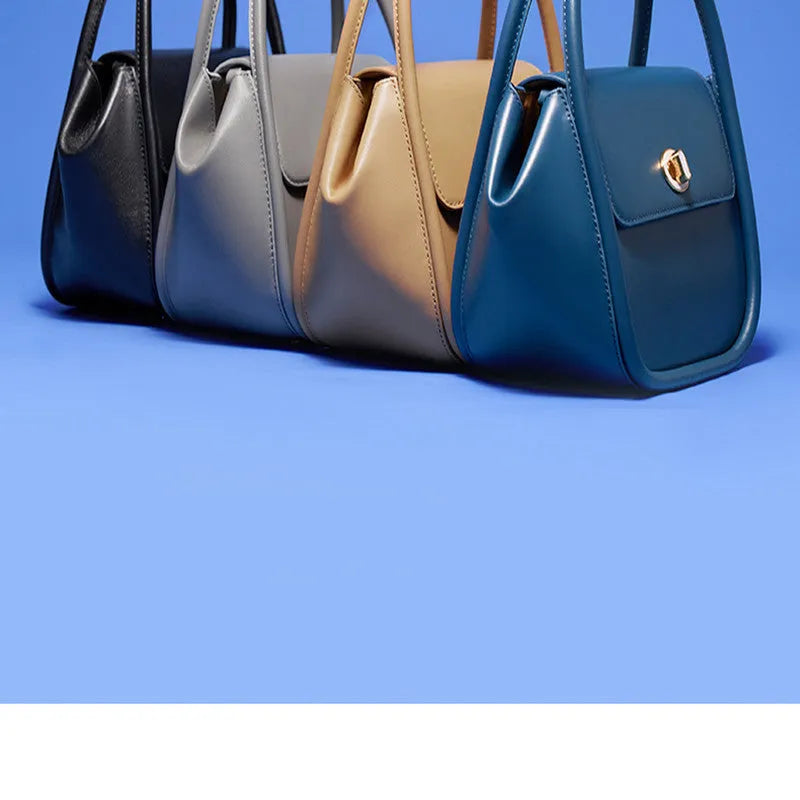 Women's wing-shaped leather tote bag with a latch buckle, shown in Atlantic blue with a cross-body strap.