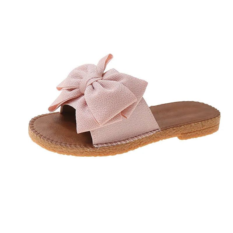 Women's beige suede slip-on sandals with bow detail and flat rubber sole