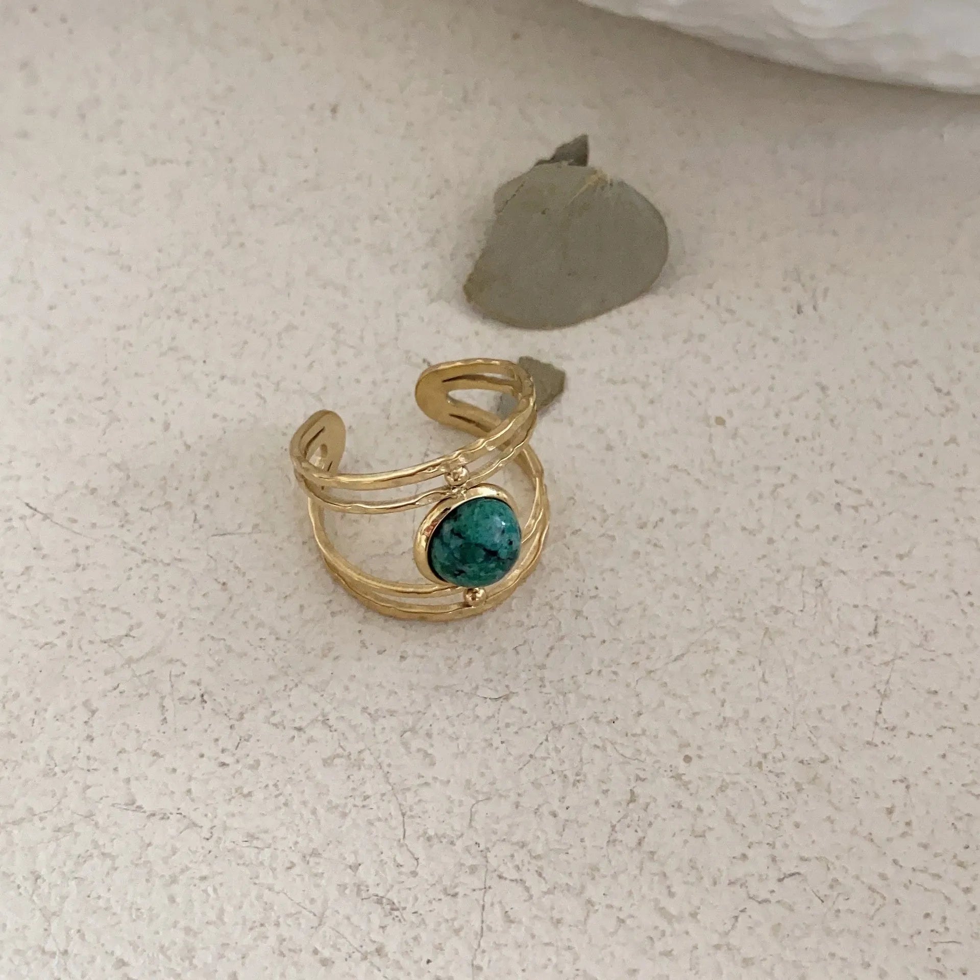 Geometric titanium steel open ring with a central natural green stone on a hand.