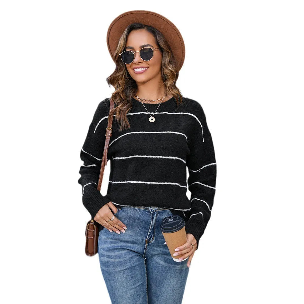 Woman wearing a black and white striped loose-fit pullover sweater with a round neckline.