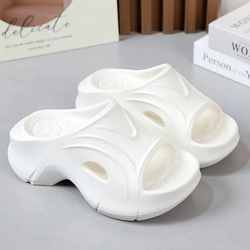 Women's white thick-soled EVA foam slippers with rounded toe on a beach.