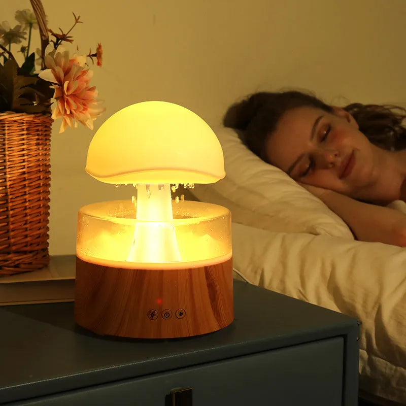 White cloud-shaped humidifier with raindrop simulation and colour-changing lights on wooden surface