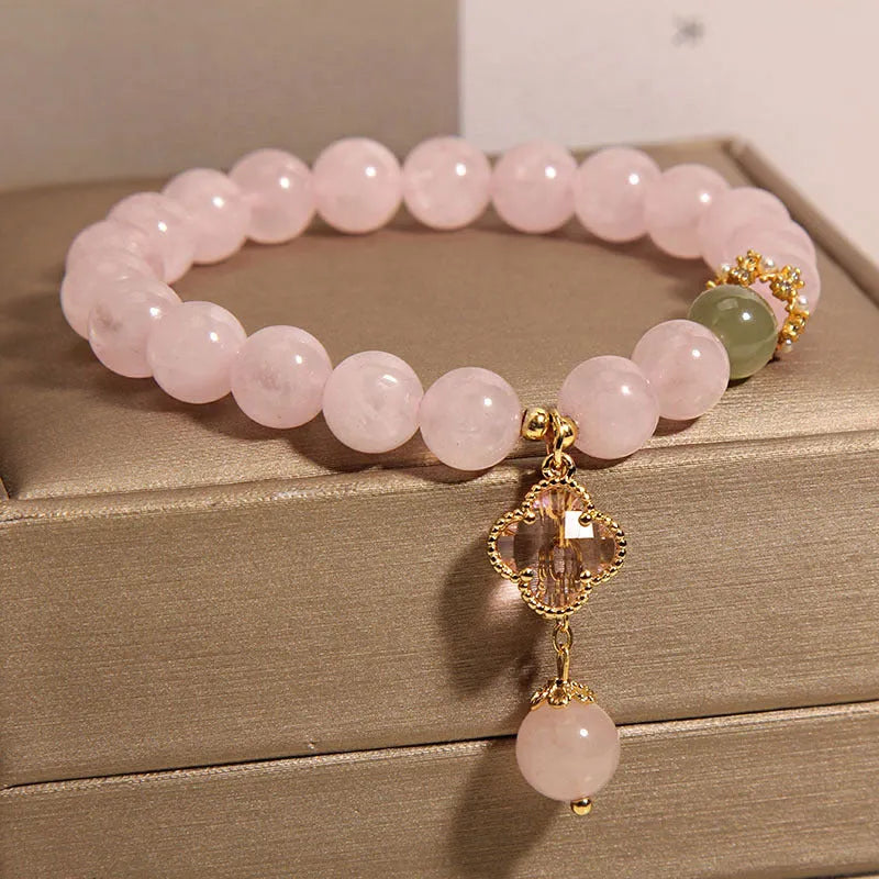 Pink crystal four-leaf clover pendant bracelet for women with rhinestones on alloy band.