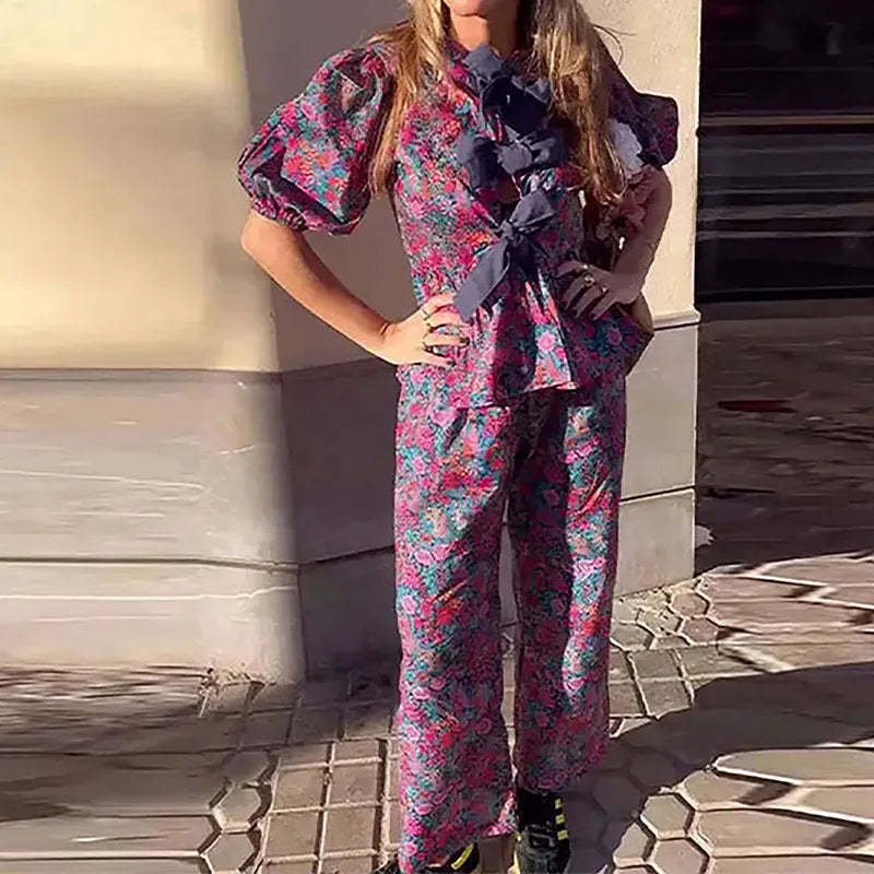 Women's floral printed trousers suit with tie-neck puff sleeve top and matching trousers in polyester fabric