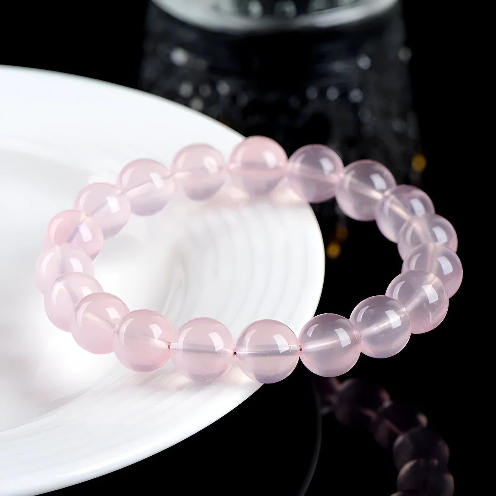 A pink natural crystal bead bracelet with polished round beads in a single circle design on a wrist.