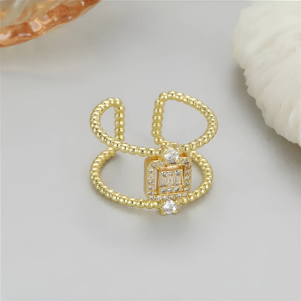 Gold-coloured adjustable open ring with an asymmetric U-shaped design on a finger.