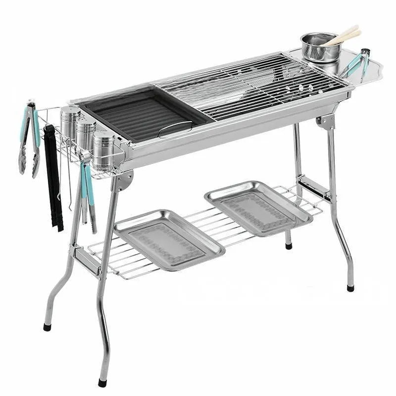 Large stainless steel turnover barbecue oven with charcoal grill and cooking accessories.