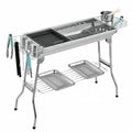Large stainless steel turnover barbecue oven with charcoal grill and cooking accessories.