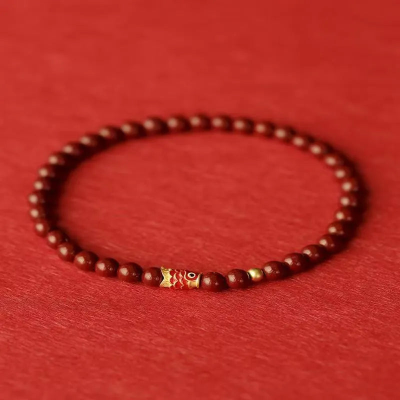 Natural cinnabar koi bracelet with golden balls in national style, showing sand grain texture