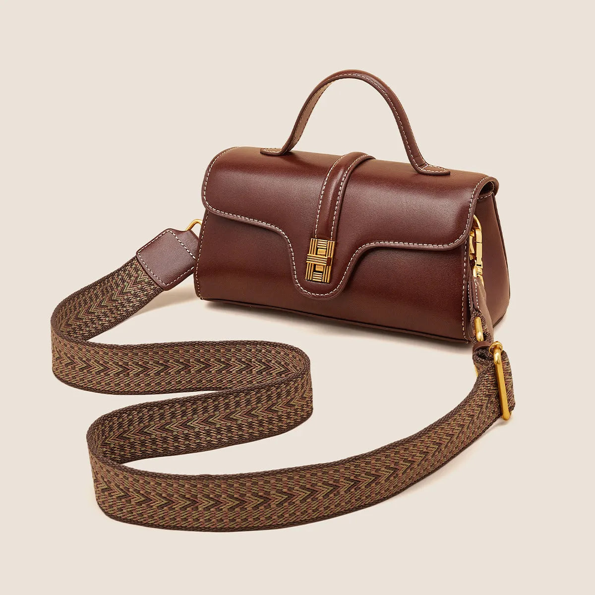 Brown Cambridge-style crossbody messenger bag with clamshell opening and lock detail on a table.