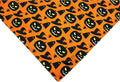 Black and orange reversible Halloween dog bandana with pumpkin and spider web patterns on a dog.