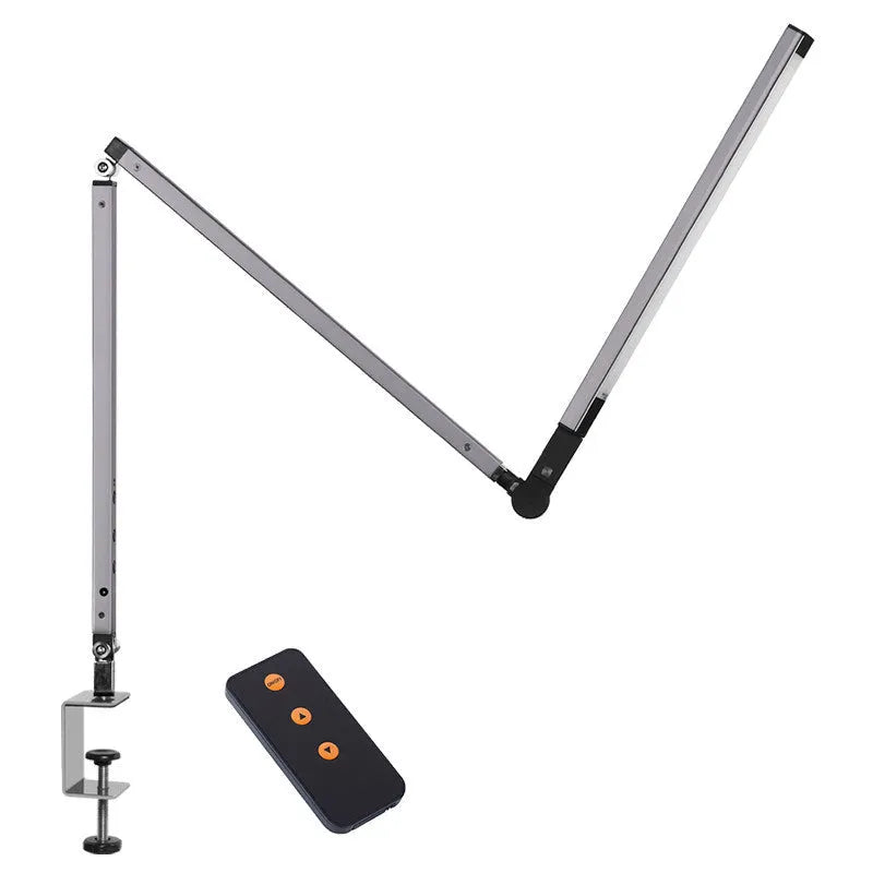 Aluminium clip-on desk lamp with adjustable arm and remote control on a wooden desk.