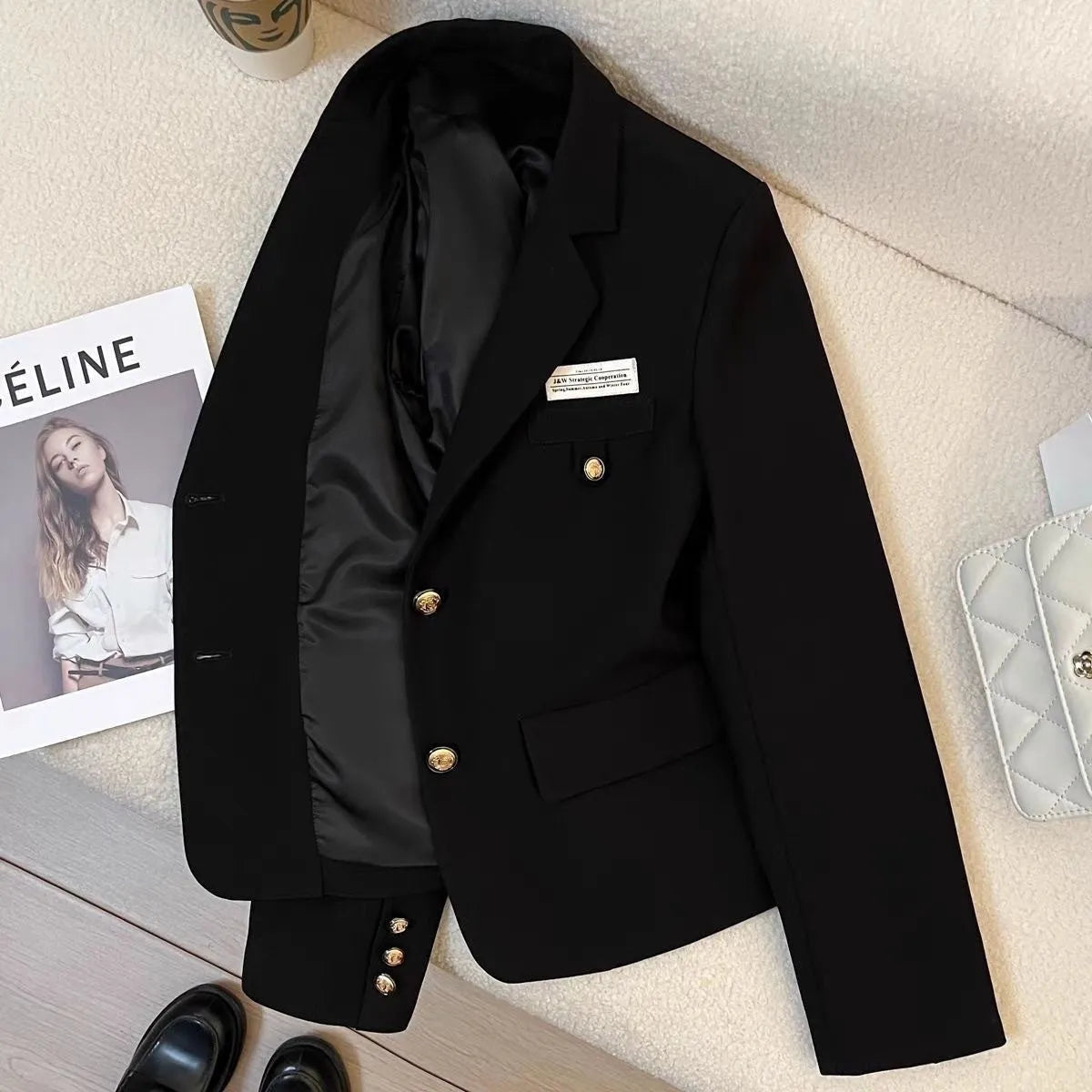Women's black short suit coat with loose fit and regular sleeves on hanger