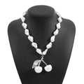 Gold coloured cherry fruit pendant necklace with imitation pearls on an adjustable chain.