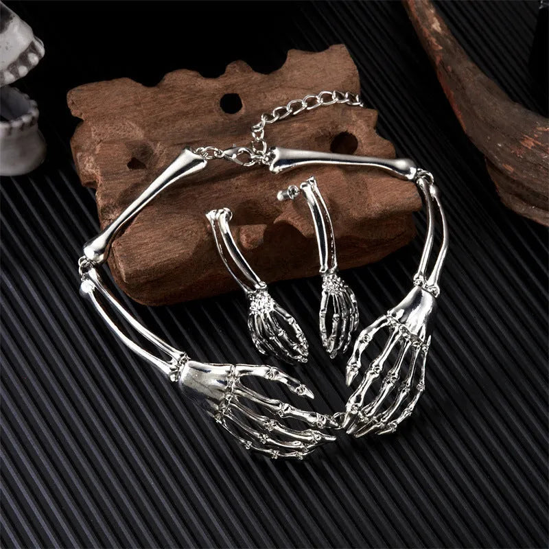 Silver alloy skull and ghost claw necklace with matching earrings set on a dark background.