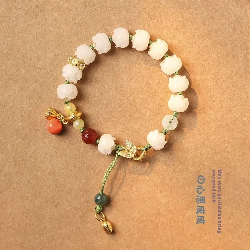 Close-up of a hand-woven white jade Bodhi bracelet with pumpkin and lotus beads on an adjustable rope.