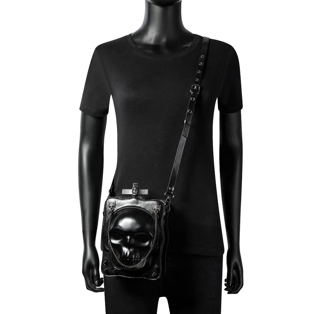 Black mini square messenger bag with a gothic embossed skull design, chain detail, and a crossbody strap.