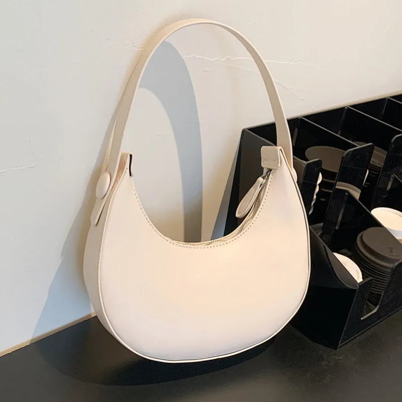 Retro dumpling-shaped black PU leather women's shoulder bag with a front sandwich pocket.