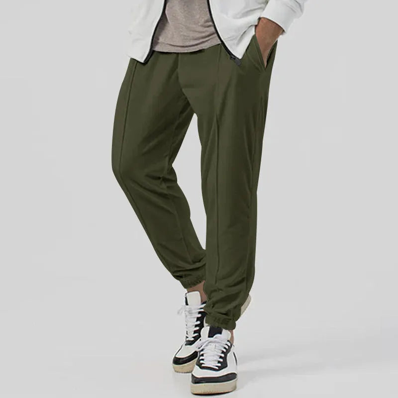 Man wearing grey loose tapered cotton blend track sweatpants, showing straight-leg style.