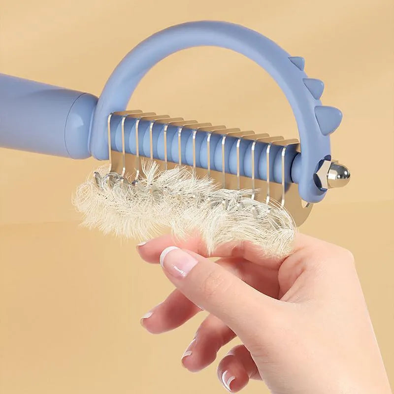 Dinosaur-shaped self-cleaning cat brush with double-sided stainless steel pins on blue handle