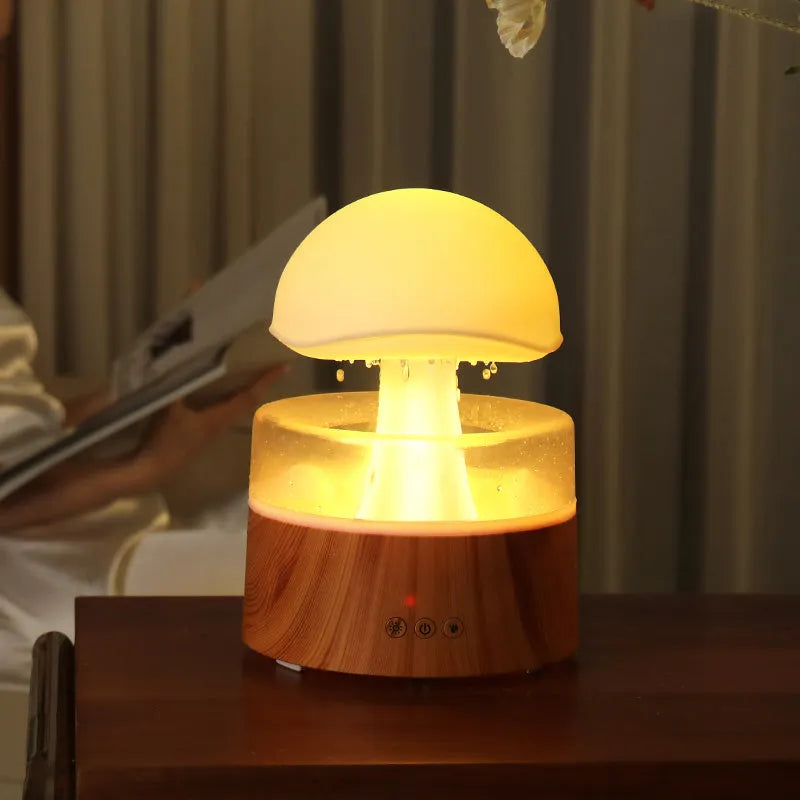 White cloud-shaped humidifier with raindrop simulation and colour-changing lights on wooden surface