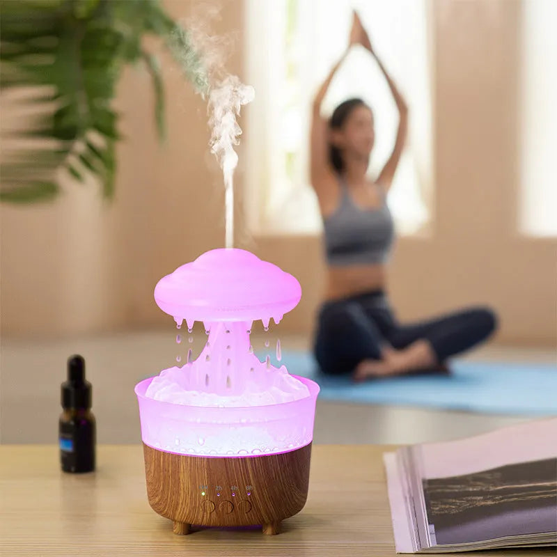 Wood grain white cloud-shaped humidifier and essential oil diffuser with coloured LED night light on a table.