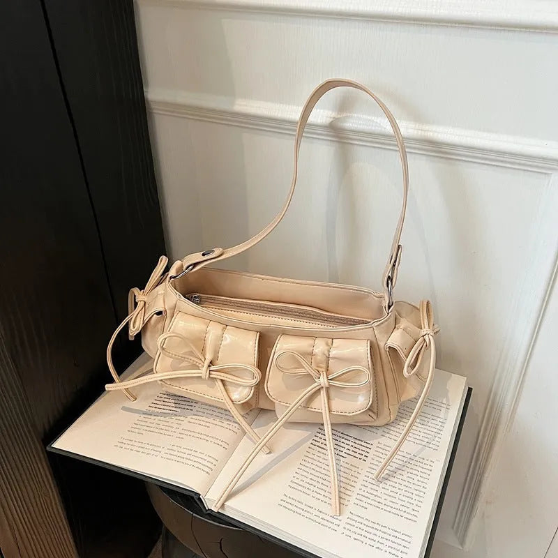 Women's pleated shoulder bag with a tassel bow, showing multi-pocket design and available in eight colours.