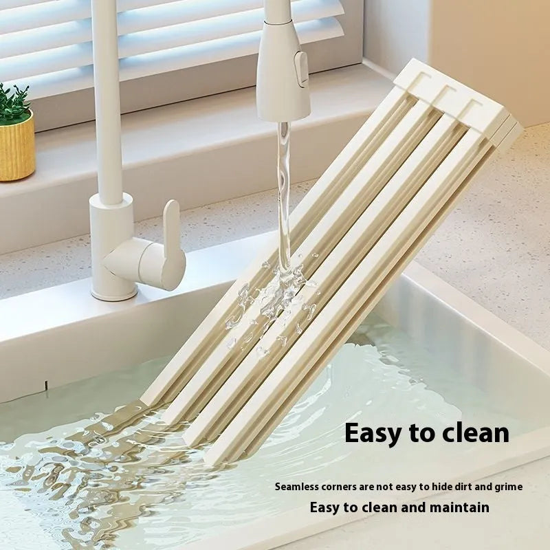 Foldable milky white stainless steel kitchen draining rack shown next to a sink.