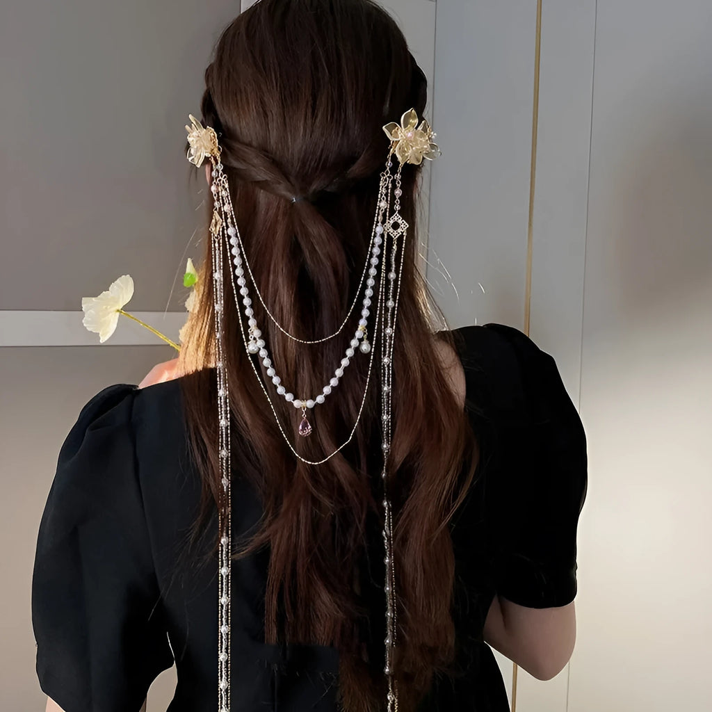 Gold acrylic women's hairpin with white flower, pearl beads, diamond accents, and a long black tassel.