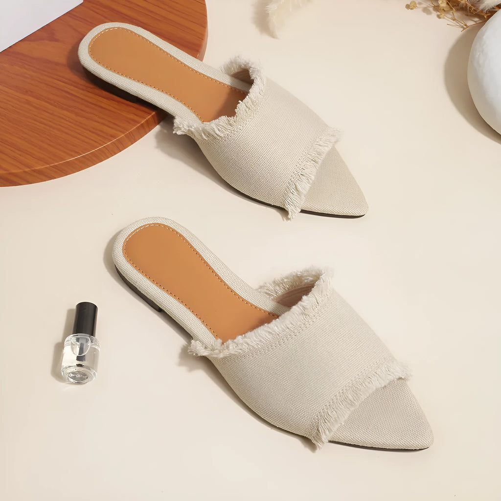 Women's apricot denim flat slippers with a tassel on the front, showing leather lining and lightweight PVC sole.