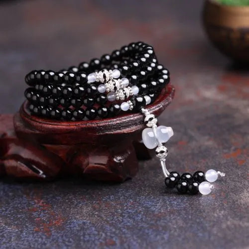 Black agate geometric bead bracelet with 108 beads and number details on a wrist.